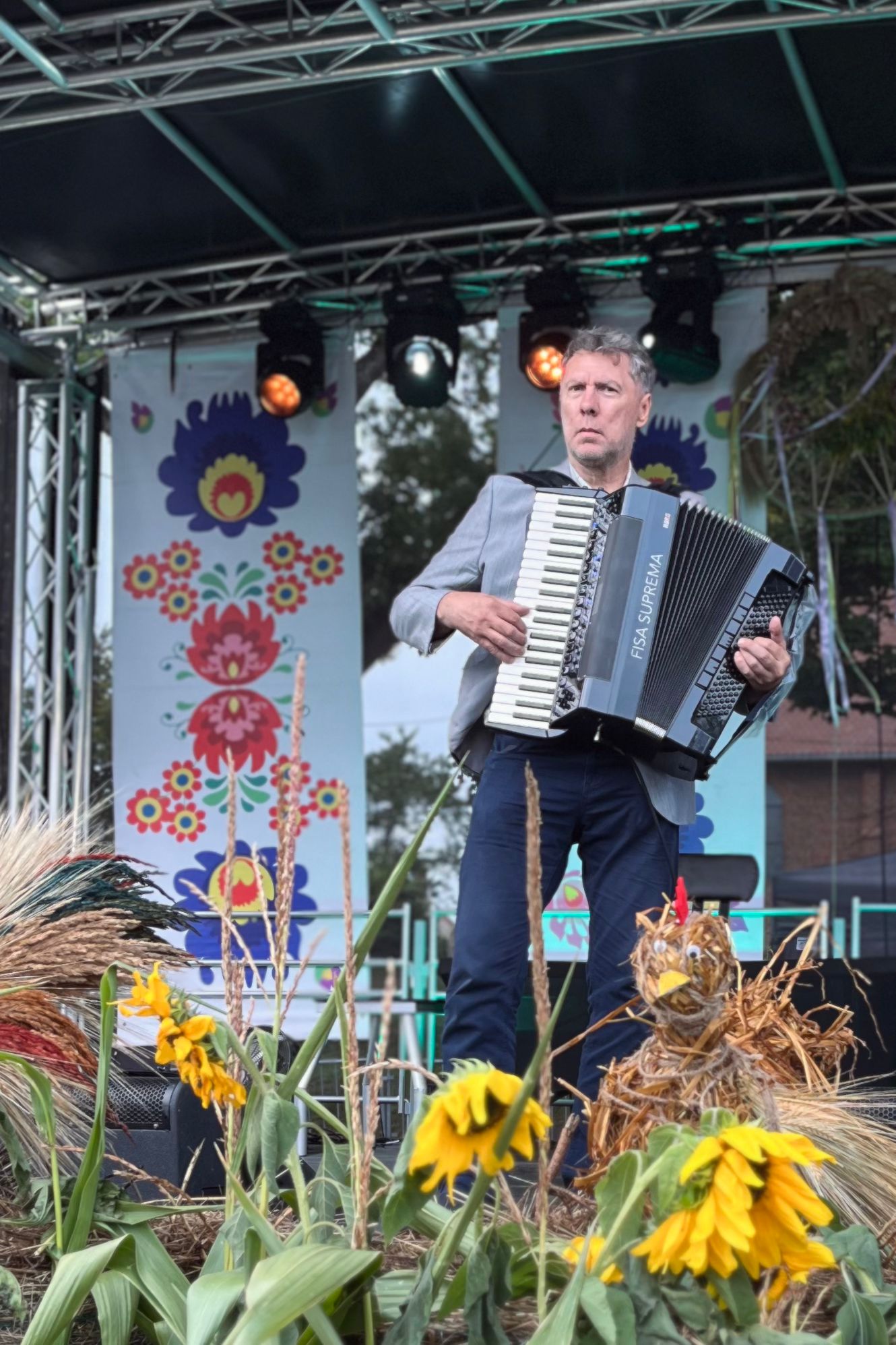 Krzysztof Szymanowski gra na akordeonie na scenie ozdobionej słonecznikami
