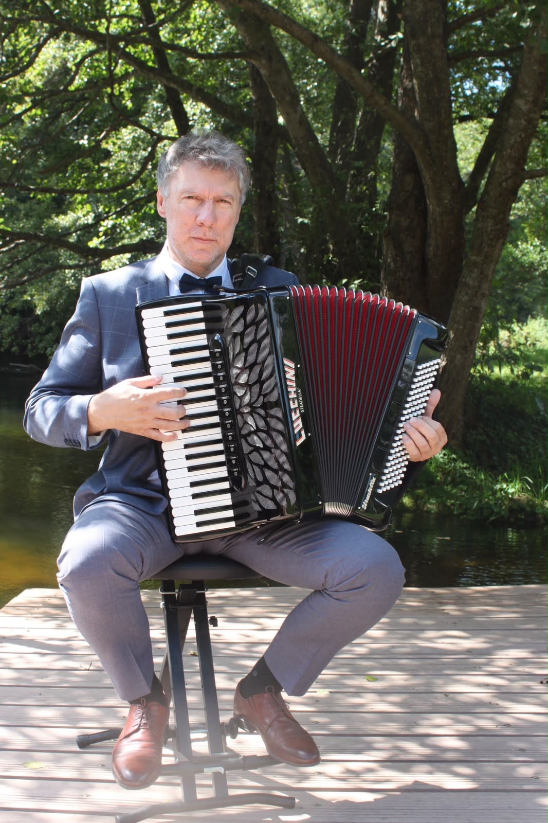 Portret Krzysztofa Szymanowskiego z akordeonem w plenerze